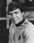 Walter Koenig smiles broadly, wearing a Star Trek uniform with an insignia badge