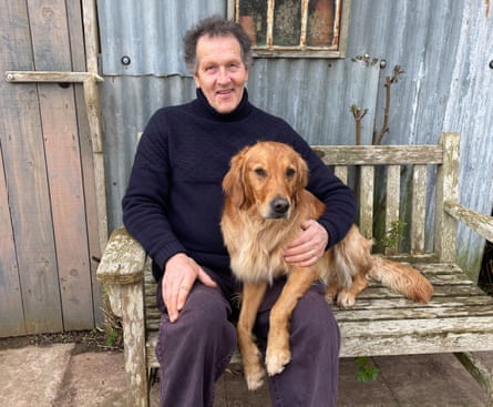 A man in a black roll-neck jumper holding a golden shaggy dog