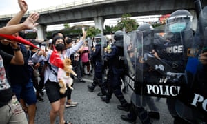 Anti-government protesters flash the three-finger salute as they face riot police during a rally in Bangkok on Wednesday