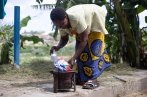 Agness Zakayo*, 47, using an empty plastic sachet to light charcoal