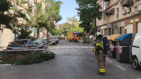 Fire brigade officer stands by destroyed car in Granada after earthquake in Spain.