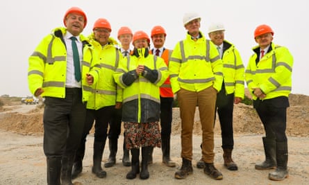 John Flint and Andrew Griffith stand among a group of people all wearing hi-vis jackets and helmets