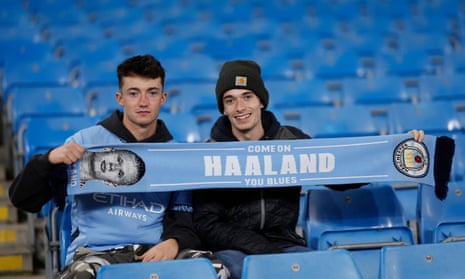 Manchester City fans hold up a Erling Haaland scarf .