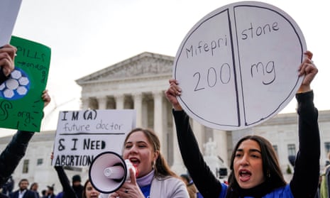 people hold signs and speak into speakerphone