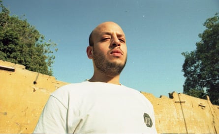 Zuli with blue sky, green trees and a yellow fence behind him.