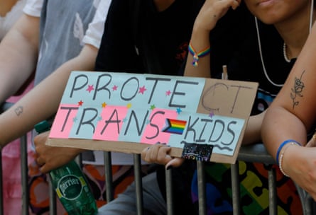 A person holding a 'Protect Trans Kids' sign