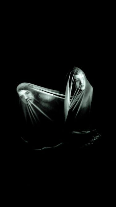 Two figures draped in translucent fabric against a black background, their faces partially visible through the material