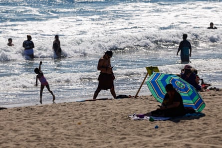 People swim and walk on the sand.