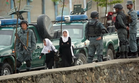 Schoolgirls walk past police forces near the blast site in Kabul