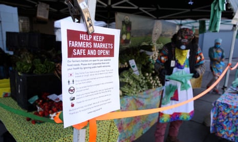 A sign about keeping the farmers market safe is posted on a vendor’s tent during the Ferry Plaza Farmers Market in San Francisco.