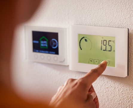 A woman adjusts smart thermostat controls on a wall