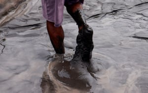 Close-up of feet wading through a river, covered in what looks like mud or oil