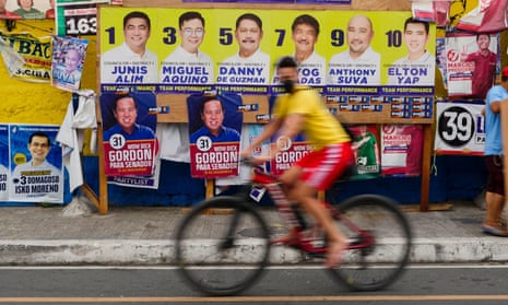 person rides bike in front of election posters
