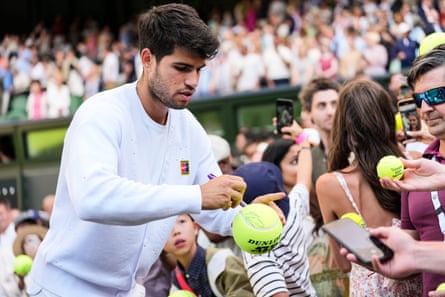 Alcaraz signs tennis balls held out to him from the Wimbledon crowd
