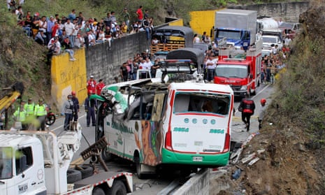 Rescuers secure a bus from falling down a ravine after an accident on the Pan-American Highway in Altos de Penalisa, near the city of Pasto, in the Colombian department of Narino.