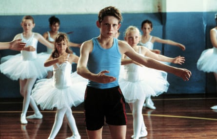A boy dancing in a room full of girls in tutus