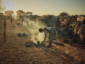 A woman stands over a small fire cooking