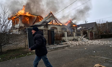 A local resident runs past a burning house hit by the Russian shelling in Kherson, Ukraine.