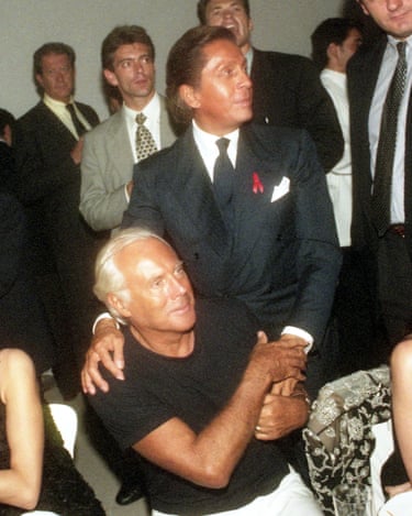 Valentino, standing, puts his hands on the shoulders of fellow designer Giorgio Armani, who is sitting down