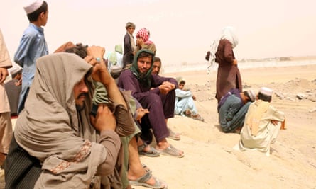 People stranded at the Pakistani-Afghan border wait by the road