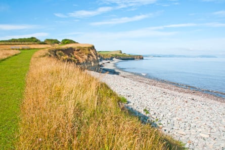 View from Kilve Beach and coast path towards St Audries Bay Blue Anchor Bay And Minehead, Somerset, South West England. Summery scene with drying grasses, rocky shore and sea.