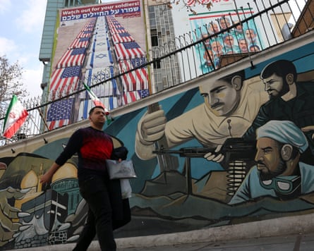 A man passes a mural depicting Iranian soldiers near an anti-US and Israel billboard in Tehran on Thursday.