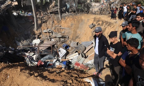 Palestinians stand on the edge of a crater after an Israeli strike on Rafah city in southern Gaza on Thursday