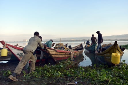 Fishermen push out a boat at dawn on Lake Victoria