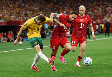 Connor Metcalfe #8 of Australia passes the ball under pressure from Hakan Calhanoglu #10 of Turkiye