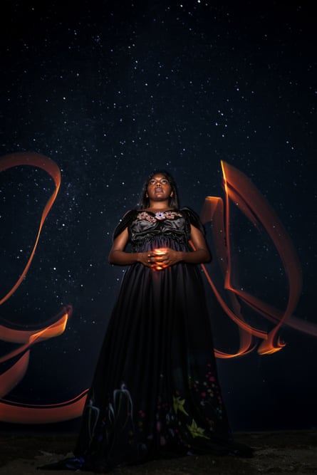 A woman in a black dress is seen in front of a starry night sky
