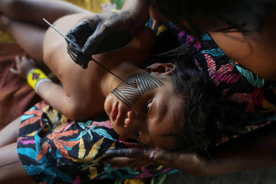 A Kayapo indigenous woman paints her daughter with a Kayapo traditional drawing in Bau village near Novo Progresso, Para state.