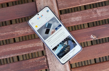 A smartphone screen on a bench showing Google Discover