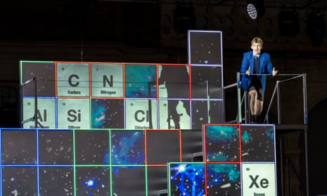 the set of itch at opera holland park, made of cubes with the periodic table projected on to it, and Adam Temple-Smith dressed as a schoolboy stood to the top right of the set, singing