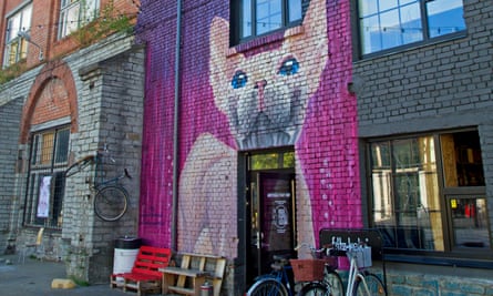 A large mural with a bright pink background painted on a building in Telliskivi