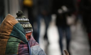 A homeless man tries to stay warm on a street on an unseasonably cold day in New York City on 15 March 2017.