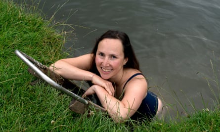 Camila Ilsley standing in the river, leaning on the riverbank and smiling at the camera above her, with a float or small bodyboard