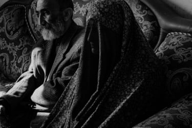 A man and a woman sitting side by side on a patterened chair