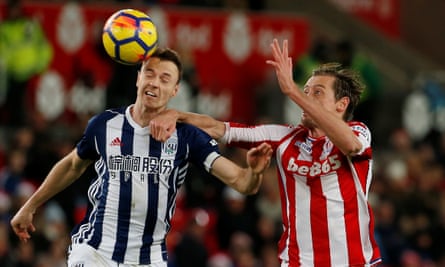 West Brom's Jonny Evans, left,  battles for the ball with Peter Crouch of Stoke