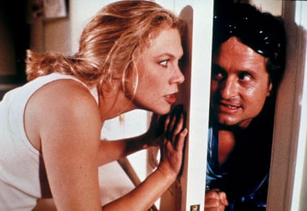 A man pokes his head around a door as a woman keeps her hand on the door.