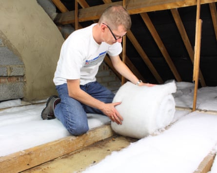 Man laying loft insulation in attic roofspace