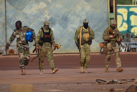 Four men in military camouflage outfits against a blue backdrop.
