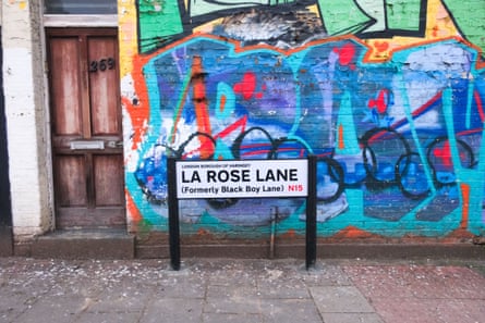 Street sign reads La Rose Lane, formerly Black Boy Lane, N19. It is in front of a wall covered in brightly coloured graffiti.