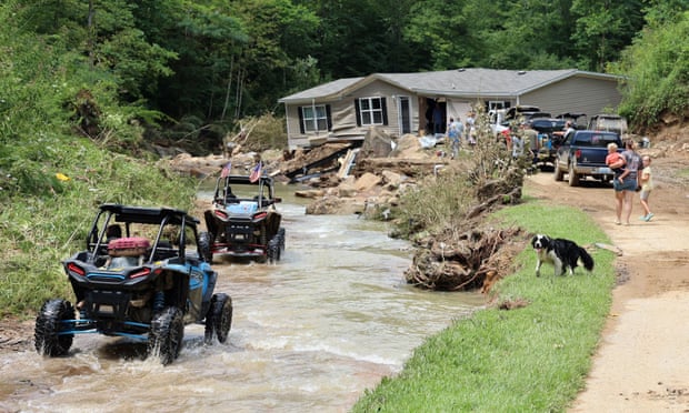 ATV drivers at a home torn from its foundations during flooding and left in the middle of the road, along Bowling Creek, Kentucky.