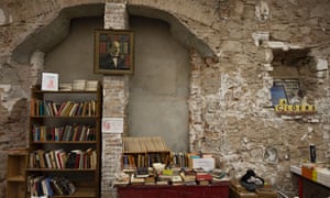 Exposed brick interior of Calders bookshop in Barcelona, with books stacked and on shelves.