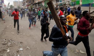 Protesters carry sticks as they run along a street in Mathare, a slum area north of Nairobi