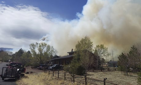 Smoke from a wind-whipped wildfire rises above neighborhoods on the outskirts of Flagstaff, Ariz., on Tuesday, April 19, 2022. Homes on the outskirts of Flagstaff were being evacuated Tuesday as high winds whipped a wildfire, shut down a major highway and grounded firefighting aircraft. (Sean Golightly/Arizona Daily Sun via AP)