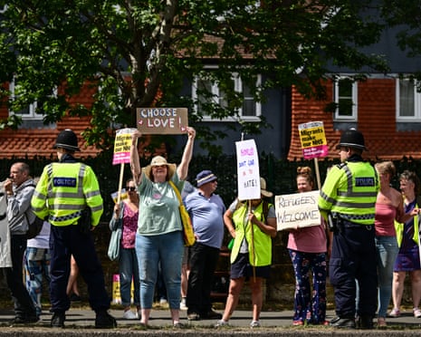People standing with signs saying 'choose love', 'refugees welcome' and 'don't give in to hate'