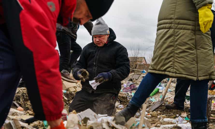 Local residents help a man clear the rubble of a home that was destroyed by a suspected Russian airstrike.