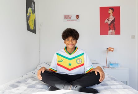 England’s united nations of football: 32 teams, one World Cup – and a lot of excited kids | World Cup 2022 28 Mark Mohammed Fall sitting crosslegged on his bed wearing a Senegal shirt, with football posters on the wall