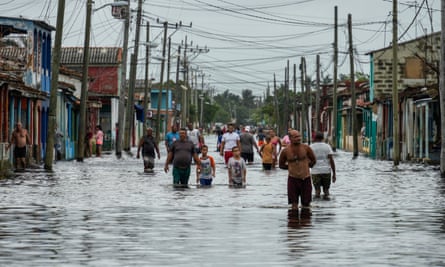 People wade through flood water in a street.